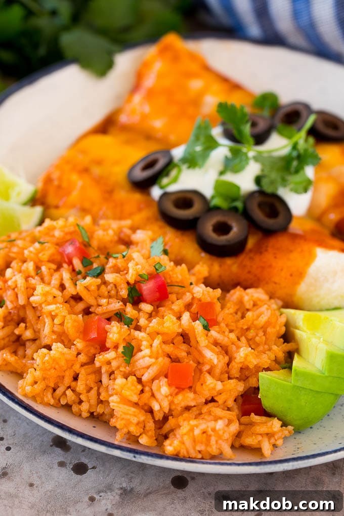 A serving of fluffy Mexican rice plated alongside savory enchiladas, showcasing a complete and appetizing meal.