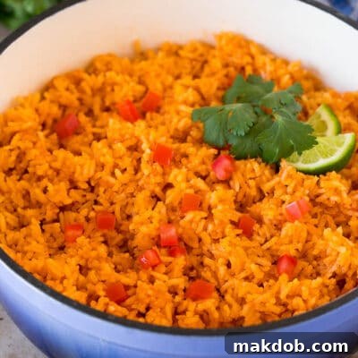 A pot of Mexican rice garnished with tomatoes, cilantro and lime wedges.