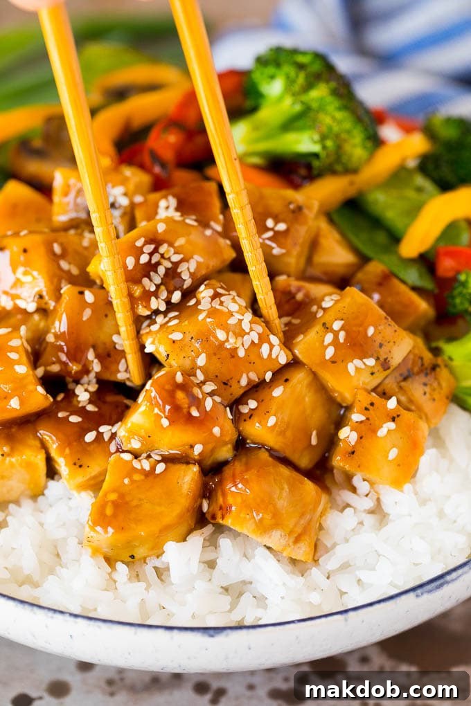 A pair of chopsticks delicately placed in a vibrant teriyaki chicken bowl, ready to be enjoyed.