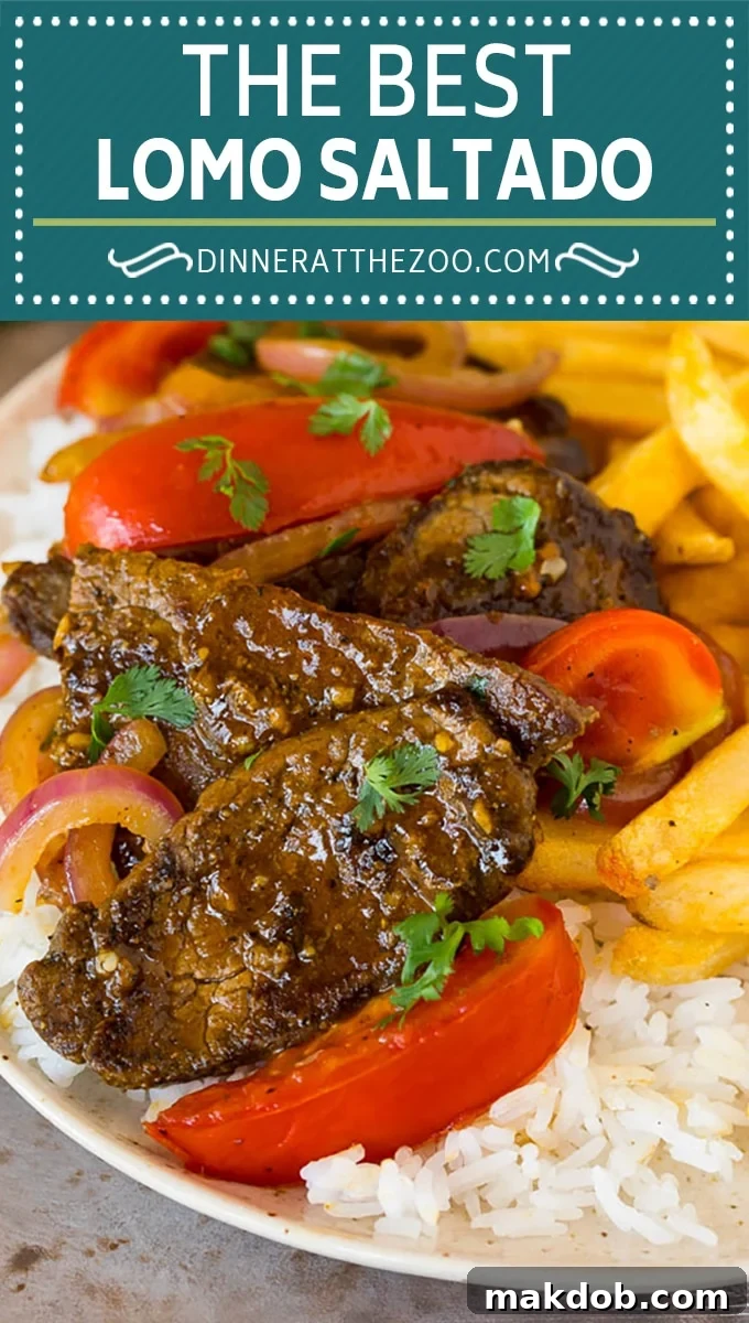 A close-up of a plate of Lomo Saltado, showcasing the vibrant colors of the beef, tomatoes, and onions, served with a side of crispy French fries and white rice.