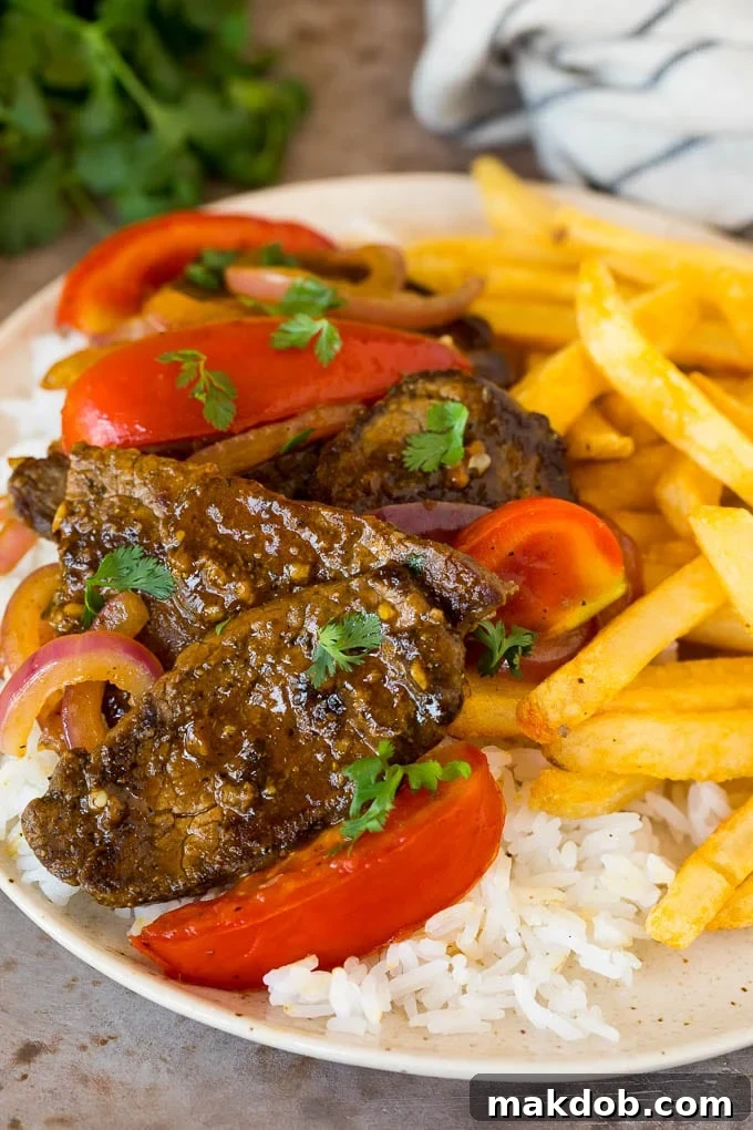 A plate of lomo saltado served with rice and french fries, ready to be enjoyed.