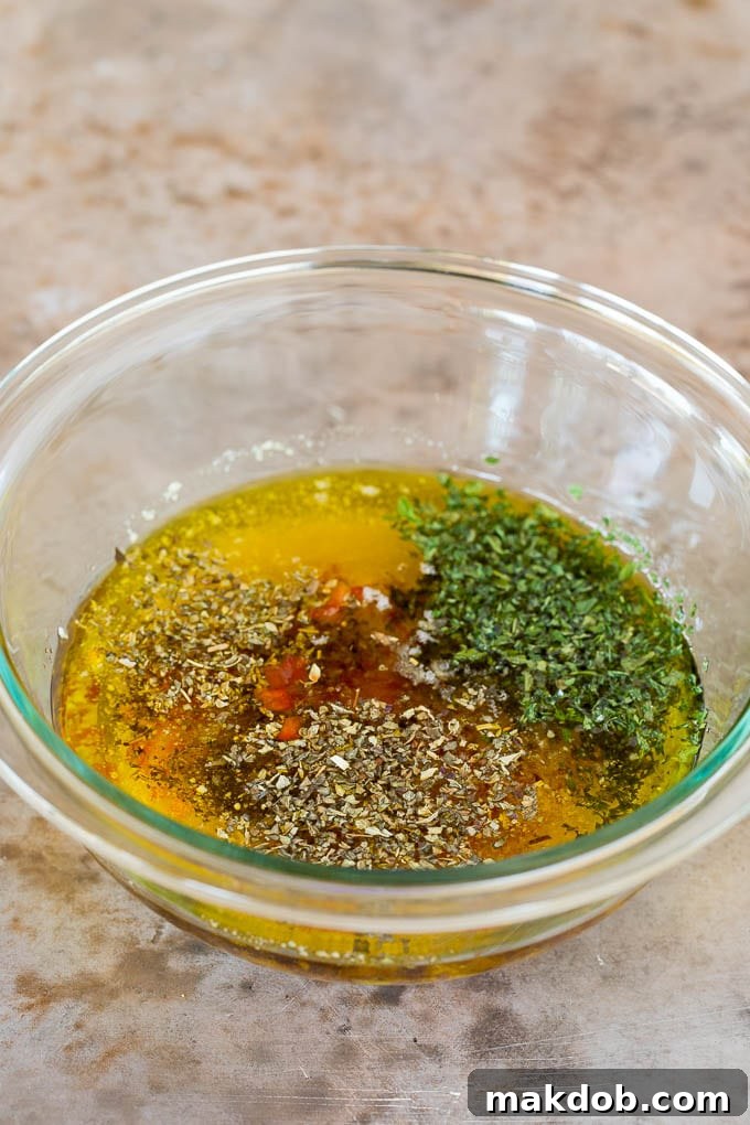 Blended Ingredients for Homemade Italian Dressing Close-up of olive oil blended with dried herbs, minced bell pepper, and grated Parmesan cheese in a bowl.