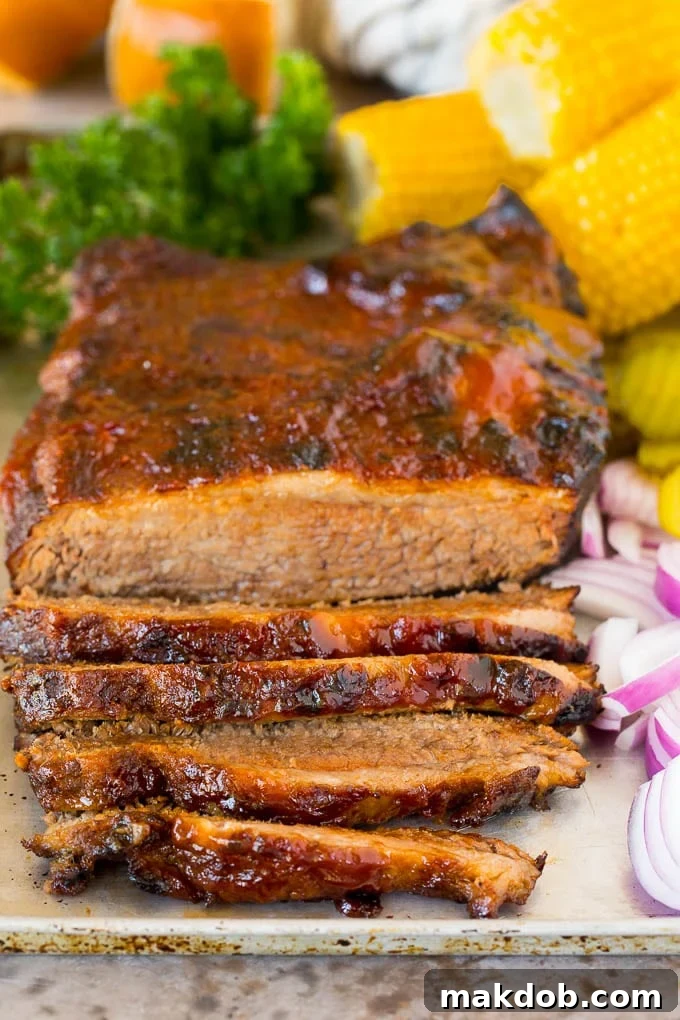 Instant Pot brisket on a tray with red onions and corn on the cob.