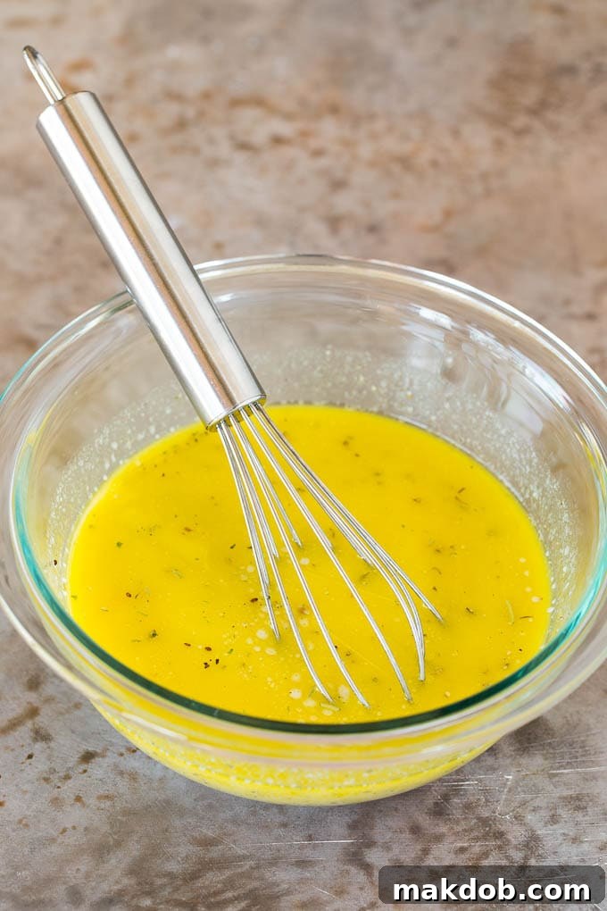 Homemade Zesty Italian Dressing A bowl of freshly prepared, creamy homemade Italian salad dressing, with a whisk resting in it, ready to be drizzled over a crisp salad.