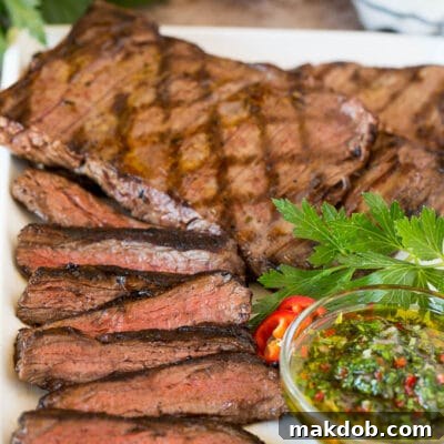 Sliced churrasco served with a bowl of chimichurri sauce.