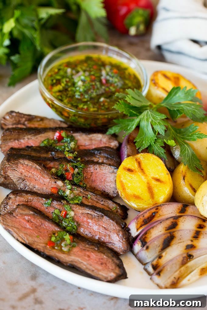 Churrasco on a plate with chimichurri sauce and a side of grilled vegetables.