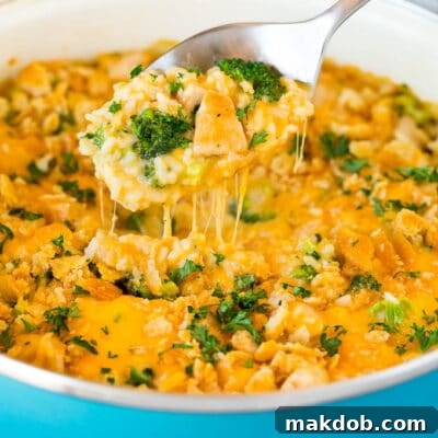 A spoon serving up a portion of cheesy chicken broccoli casserole.