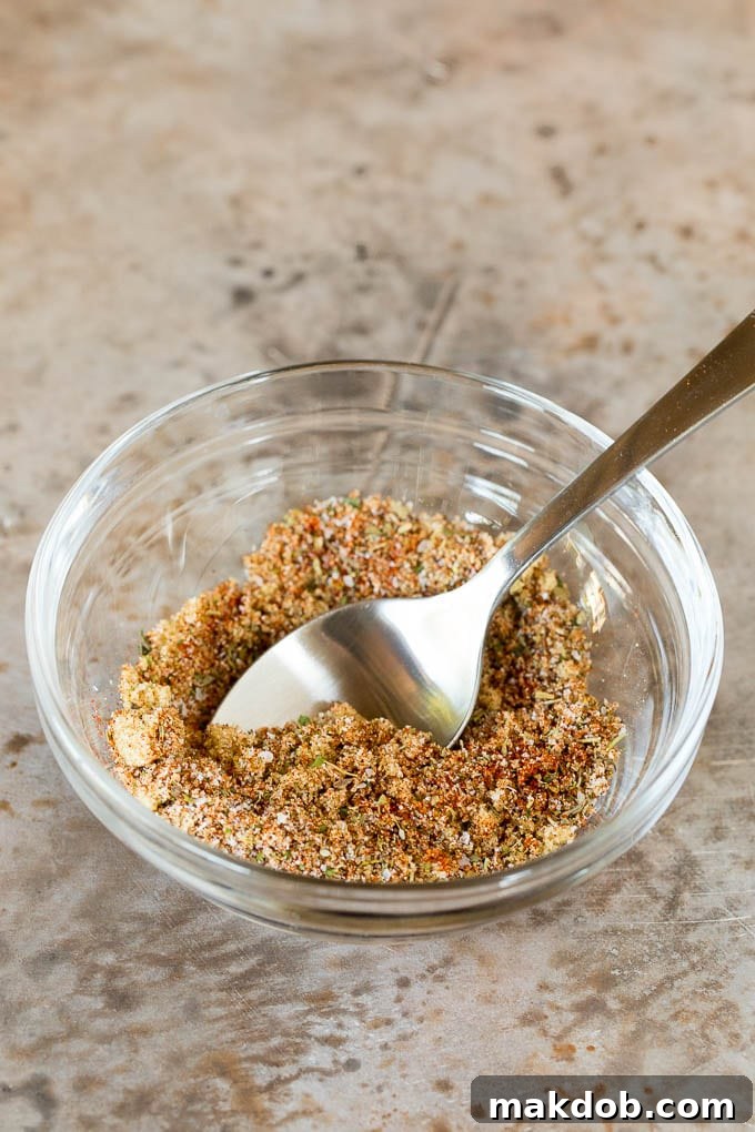 This air fryer chicken breast recipe consists of chicken coated in herbs and spices, then cooked to golden brown perfection. A bowl of chicken seasoning with a spoon in it.