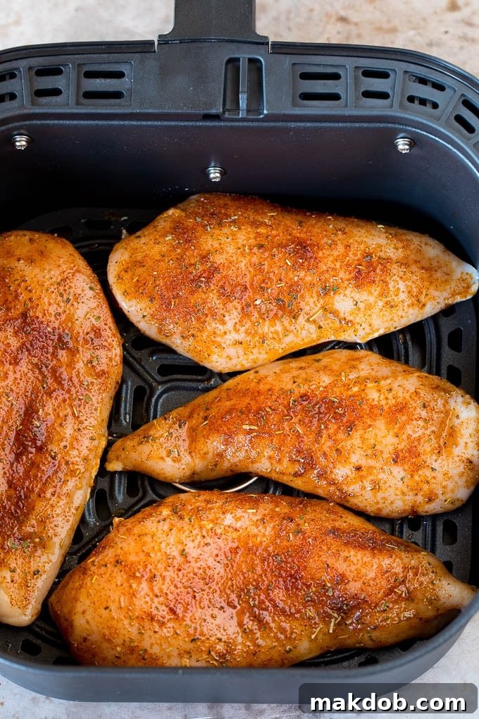 This air fryer chicken breast recipe consists of chicken coated in herbs and spices, then cooked to golden brown perfection. Seasoned chicken breasts inside an air fryer.
