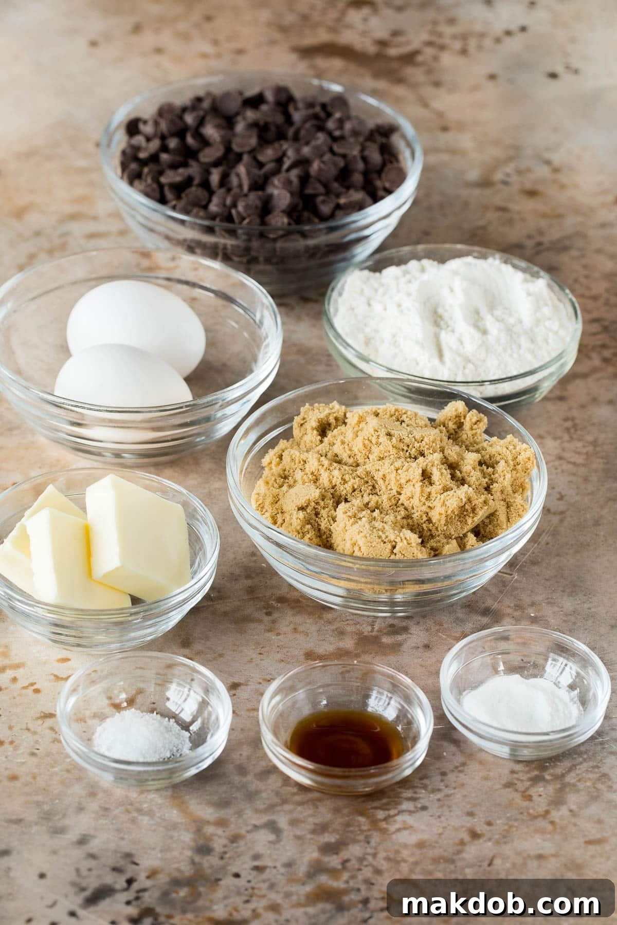 Bowls filled with essential chocolate fudge cookie ingredients: brown sugar, chocolate chips, all-purpose flour, creamy butter, and fresh eggs.