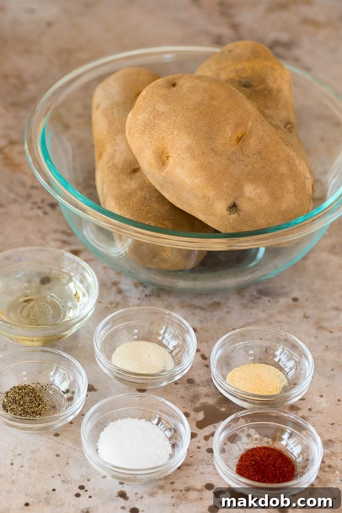 Glass bowls of potatoes, oil and spices. Glass bowls containing raw potato sticks, vegetable oil, and various spices.