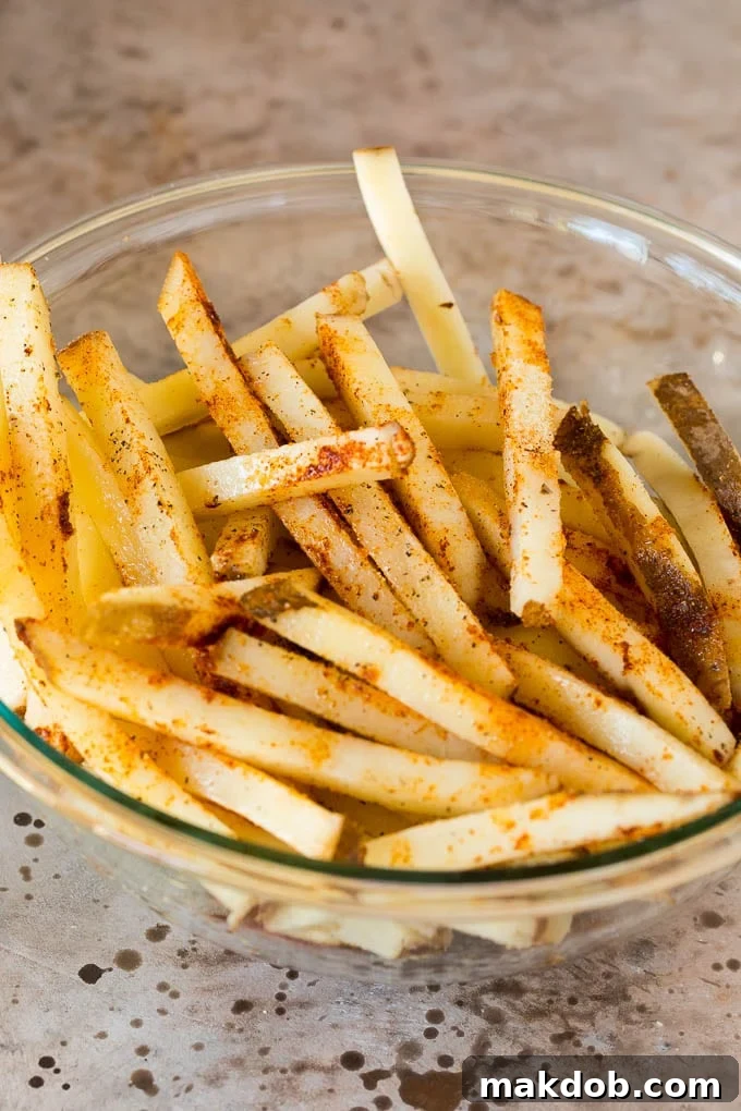 Potato sticks coated in spices and vegetable oil. Raw potato sticks coated with various spices and vegetable oil, ready for air frying.