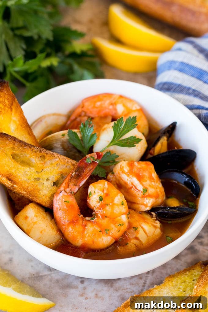 A serving bowl of cioppino with grilled bread slices in it.