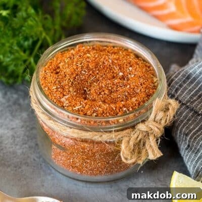 Signature Salmon Seasoning Blend 7 A jar of salmon seasoning with salmon, lemon wedges and parsley in the background.