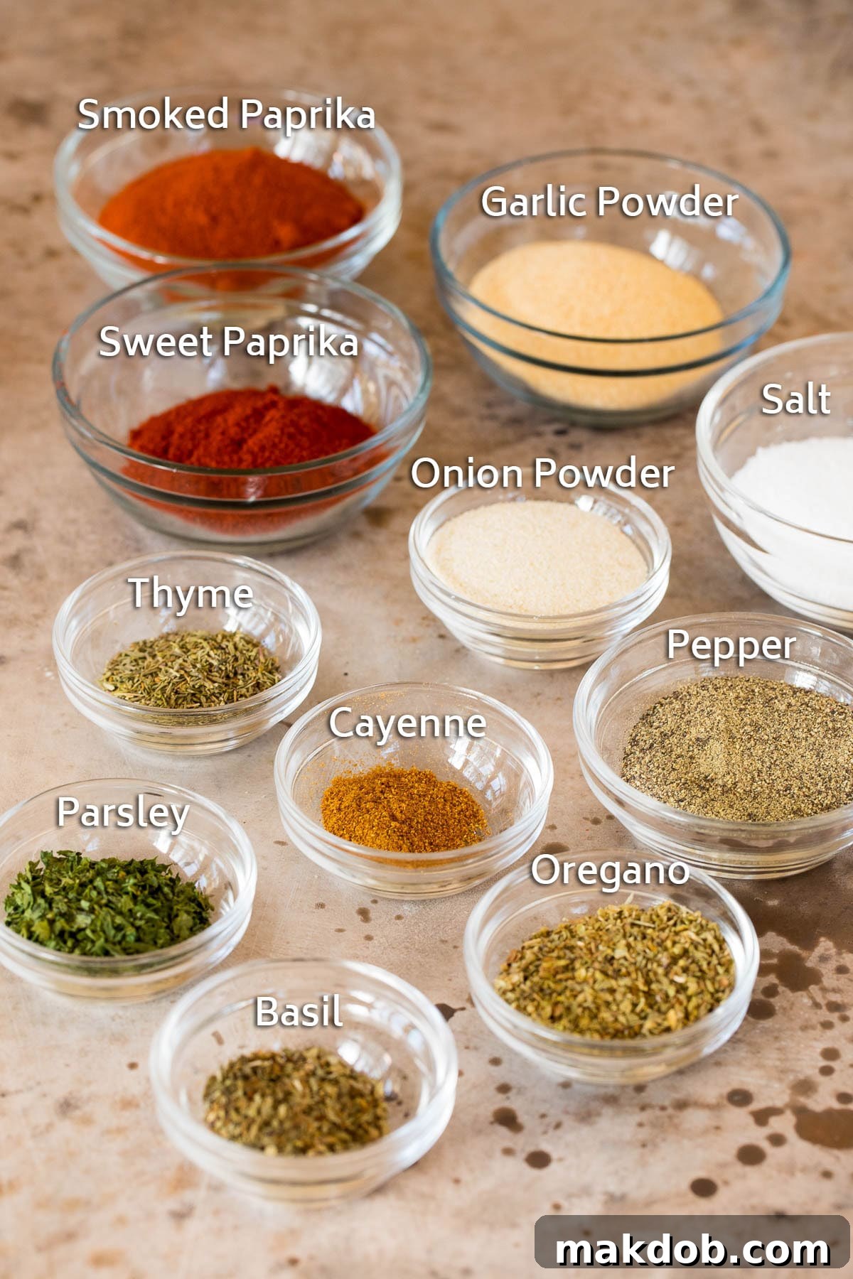 Bowls of various dried herbs and spices, meticulously arranged for making Creole seasoning, highlighting the individual components.