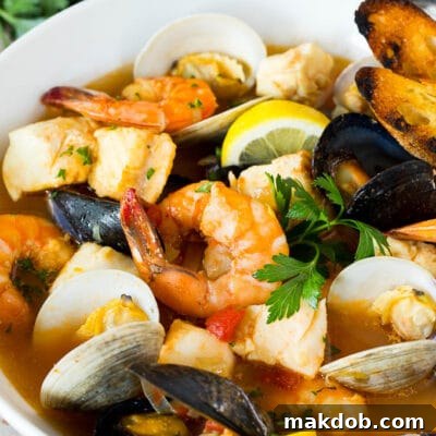 A serving bowl of bouillabaisse with shrimp, clams and fish.