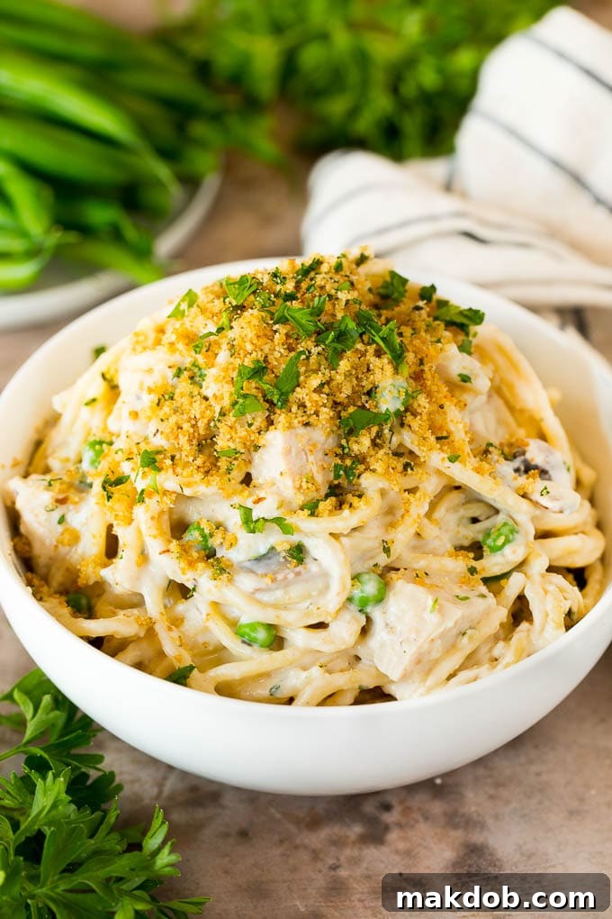 This turkey tetrazzini contains diced turkey, mushrooms and peas, all tossed with pasta in a creamy sauce, then baked to perfection. A bowl of turkey tetrazzini topped with breadcrumbs and fresh parsley, ready to eat.