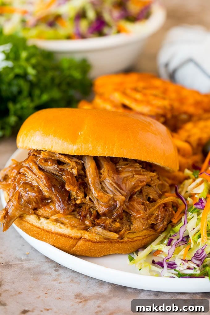 Instant Pot pulled pork on a sandwich with a side of fries and coleslaw, showcasing its tender texture and delicious appearance.