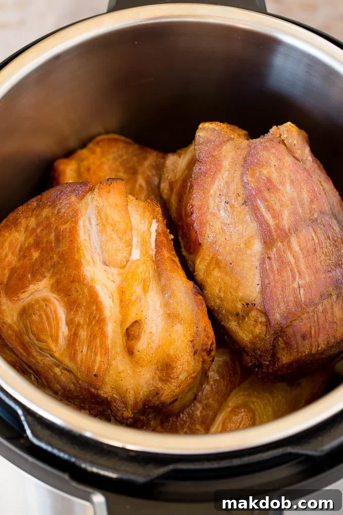 Seared pork pieces cooking in an Instant Pot, showing the browning process.