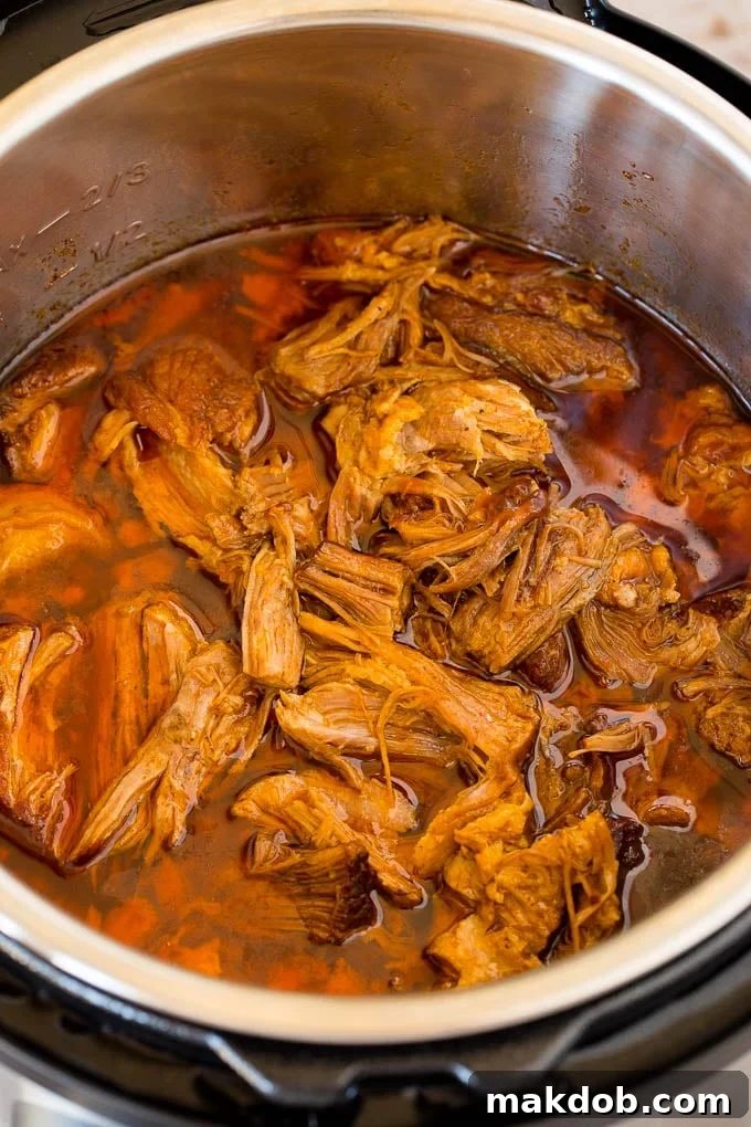 Shredded pork mixed with sauce inside an Instant Pot, ready to be served.