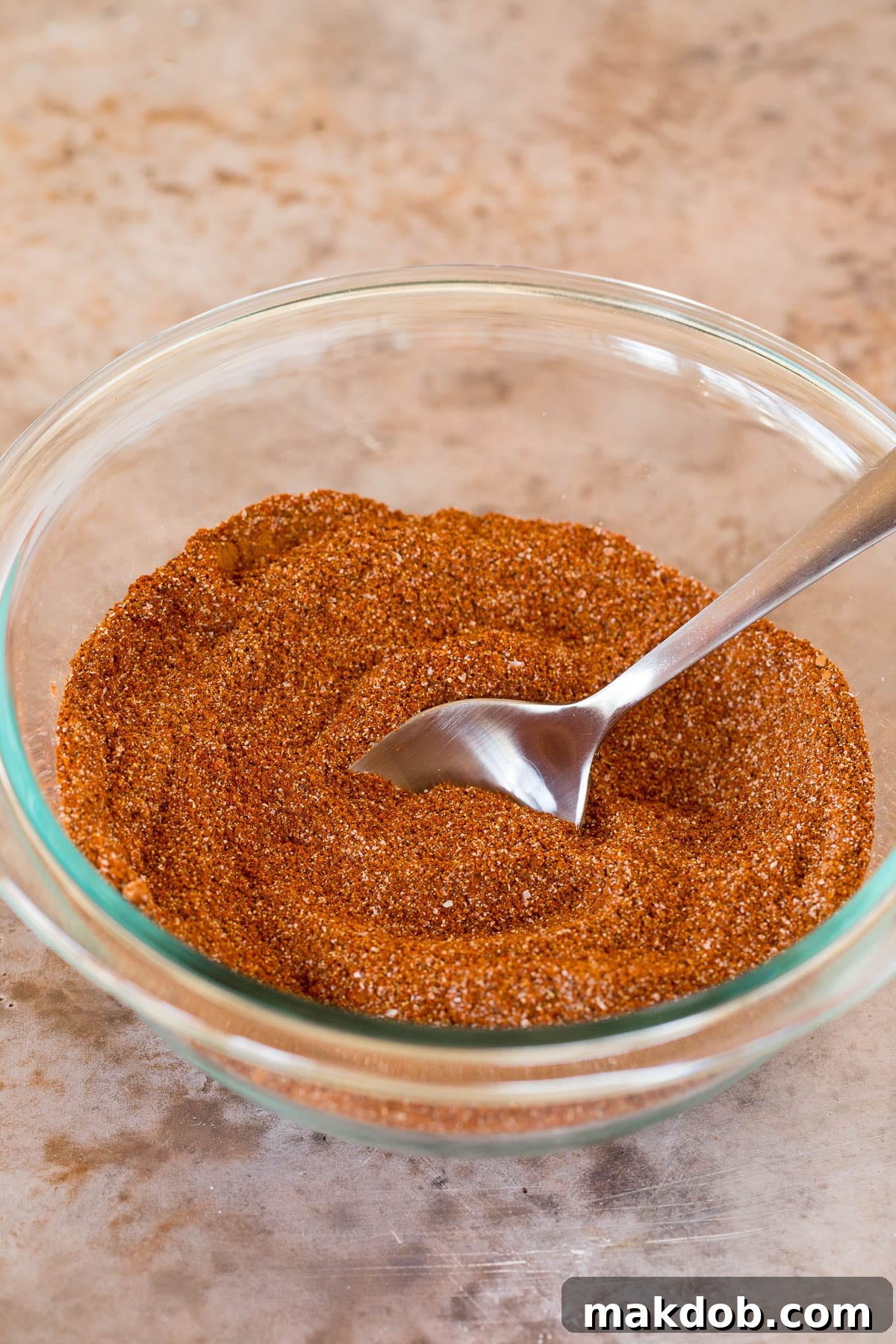 A bowl of seasoning with a spoon in it, showcasing the homemade chili seasoning.