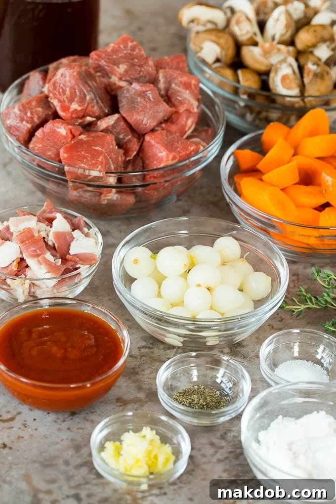 This slow cooker beef bourguignon is tender beef chunks, bacon, mushrooms, carrots and pearl onions, all simmered together in a rich red wine broth. Bowls of beef, vegetables and seasonings.