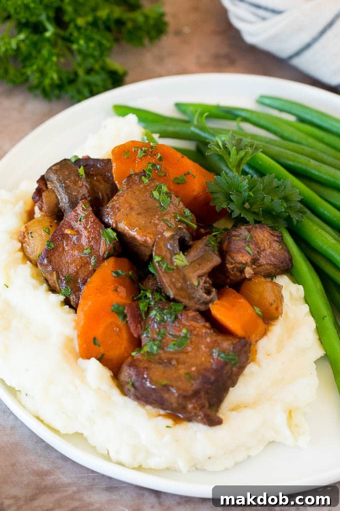 This slow cooker beef bourguignon is tender beef chunks, bacon, mushrooms, carrots and pearl onions, all simmered together in a rich red wine broth. Slow cooker beef bourguignon with mashed potatoes and green beans.