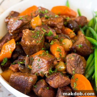 Slow cooker beef bourguignon in a bowl served with green beans.