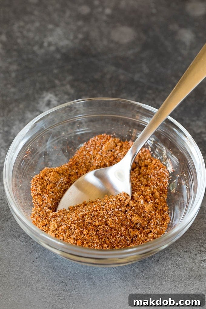 This air fryer salmon is fresh fish fillets topped with a homemade spice rub, then cooked to golden brown perfection. A spice blend in a bowl with a spoon.