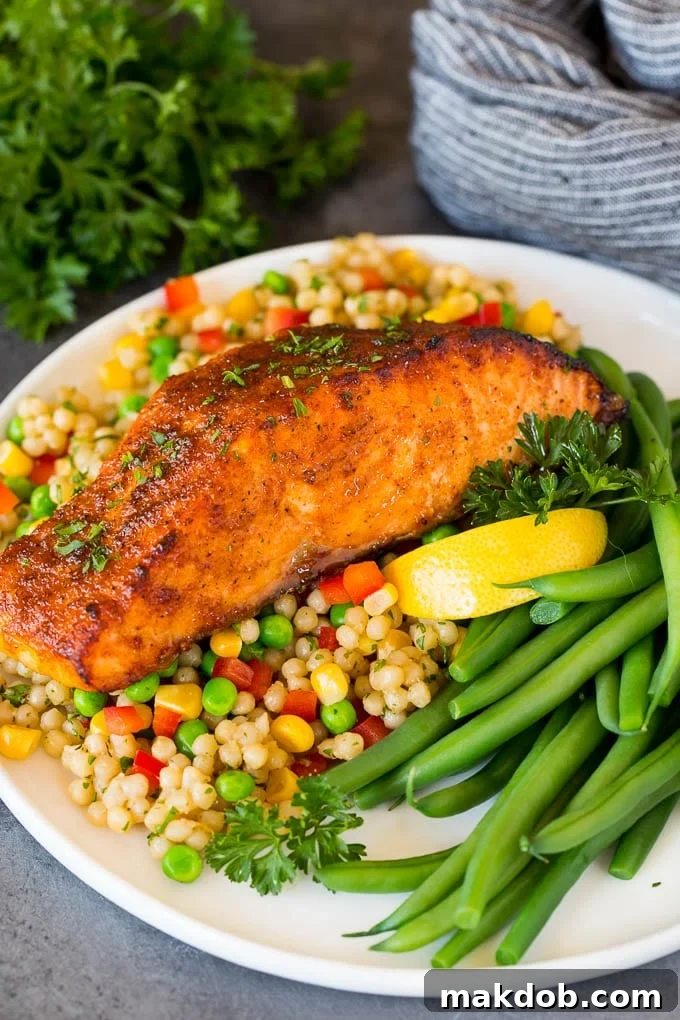 This air fryer salmon is fresh fish fillets topped with a homemade spice rub, then cooked to golden brown perfection. A piece of air fryer salmon served with couscous and green