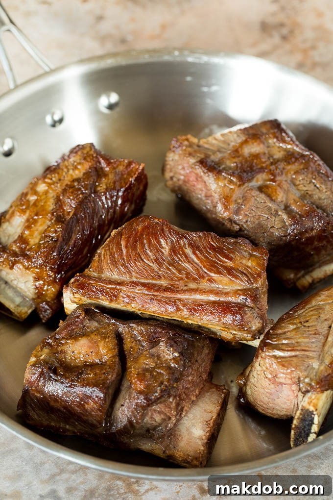 Fall-Off-The-Bone Slow Cooker Short Ribs 4 Seared short ribs in a pan.