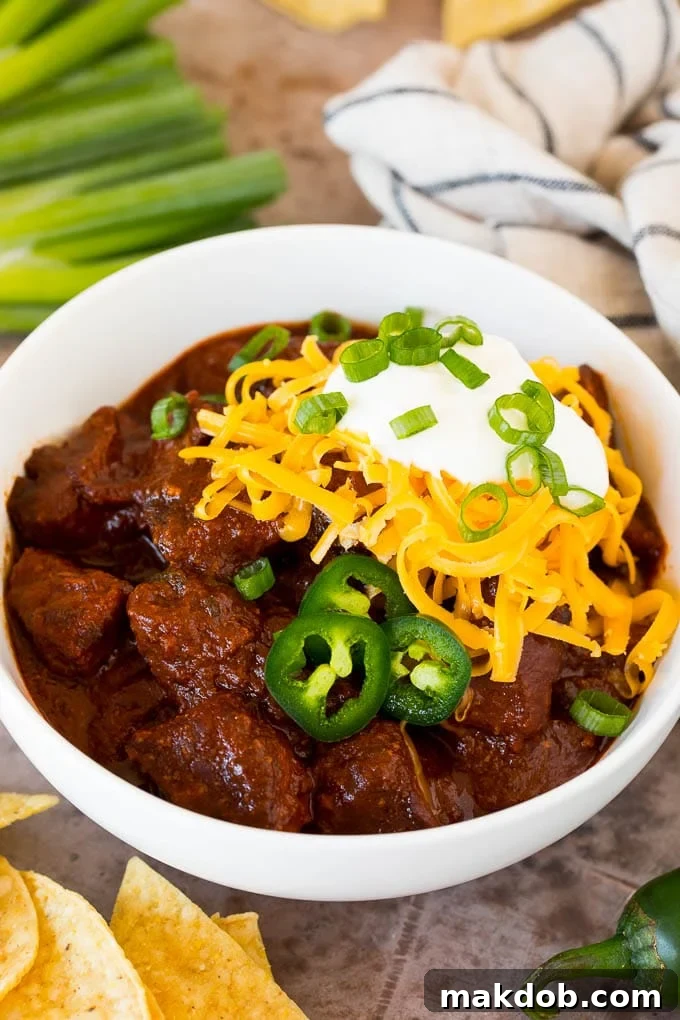 A steaming bowl of authentic Texas chili, generously topped with shredded cheese and a dollop of sour cream, promising a rich and satisfying meal.