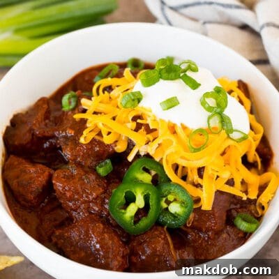A bowl of Texas chili topped with cheese and sour cream.