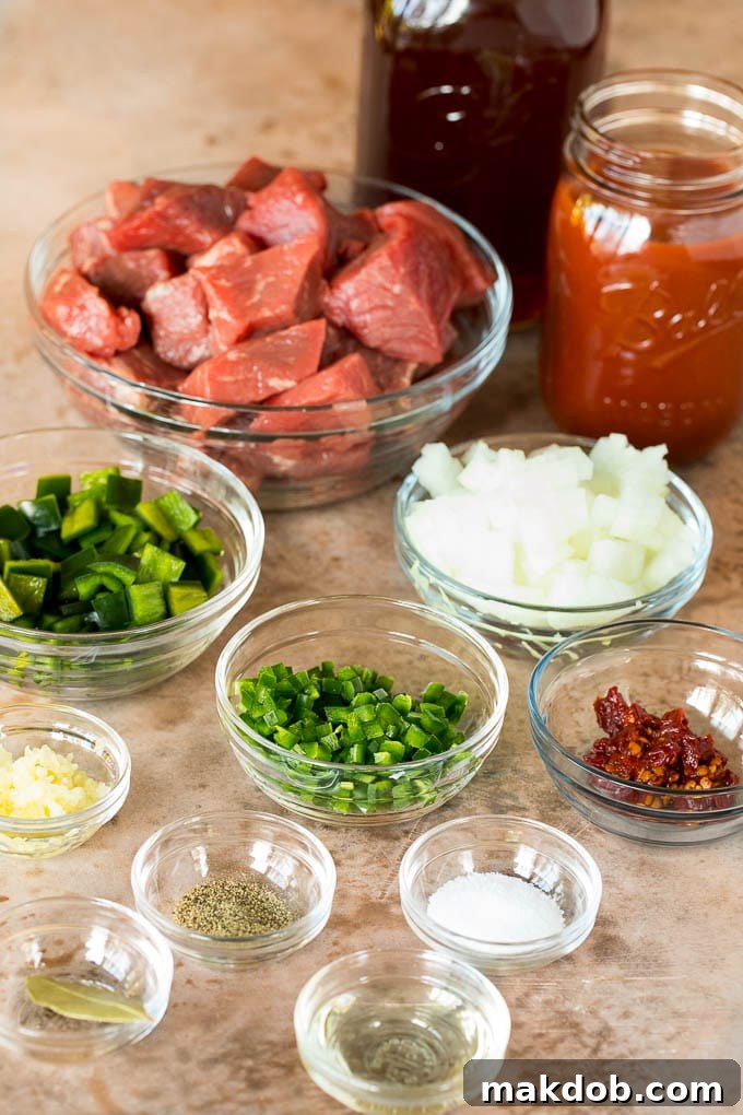 Bowls filled with individual ingredients for Texas chili, including cubed beef, sliced peppers, chopped onions, and a variety of colorful spices.