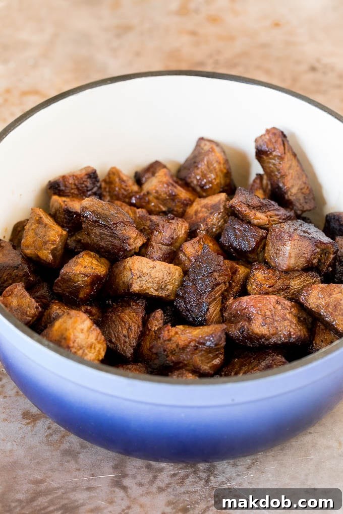 Close-up shot of perfectly seared beef chunks resting in a large pot, ready for the next steps of chili preparation.