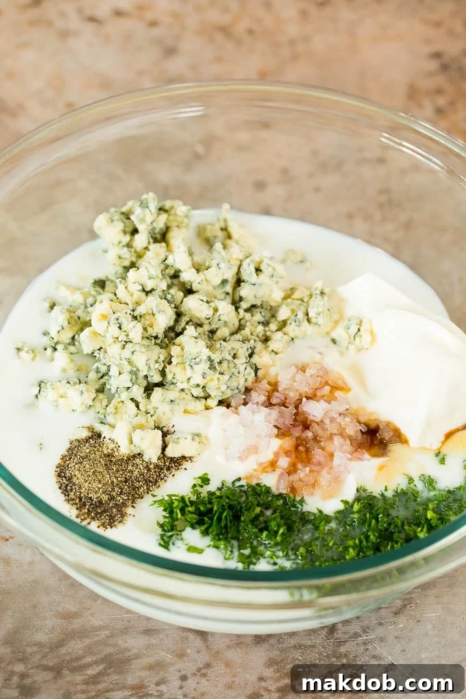 Dairy products, spices, and fresh parsley meticulously arranged in a bowl, ready for mixing to create blue cheese dressing.