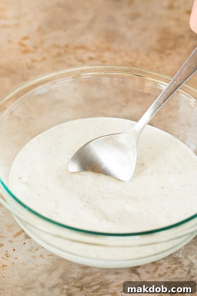 A serving spoon dipped into a bowl of creamy blue cheese dressing, ready to be enjoyed.