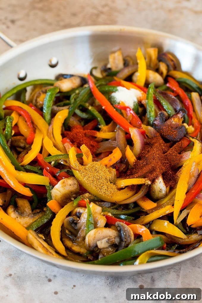 Plant-Powered Fajitas 5 A close-up view of sautéed onions and peppers, freshly seasoned with a vibrant sprinkle of spices, showcasing the rich flavors developing in the pan.