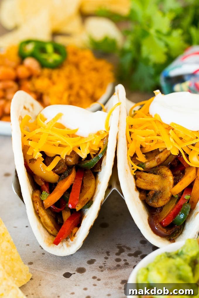 Plant-Powered Fajitas 6 Two perfectly assembled vegetarian fajitas, generously topped with shredded cheese and a dollop of cool sour cream, nestled in warm tortillas.