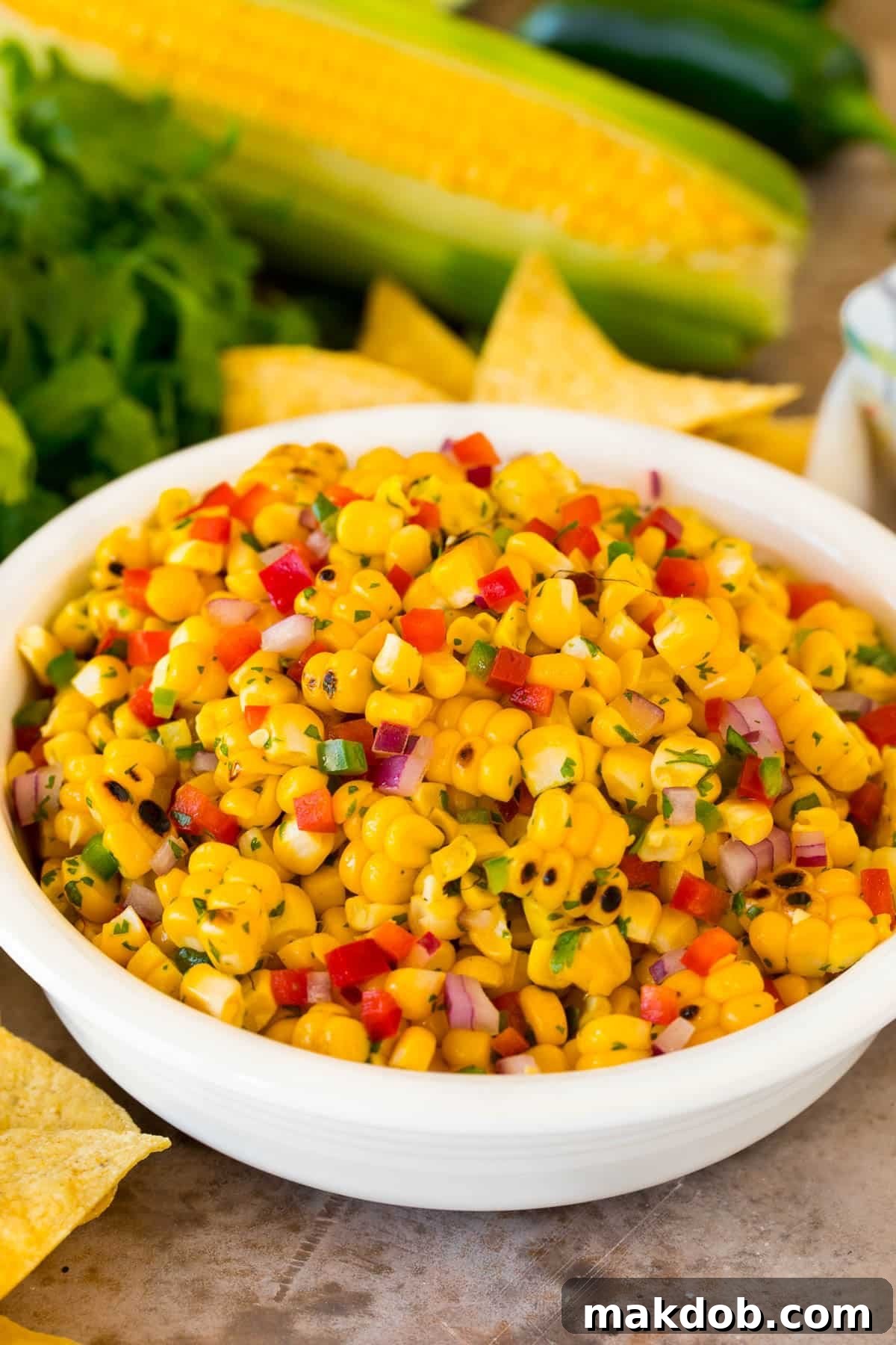 A bowl of fresh corn salsa surrounded by crispy tortilla chips, inviting a delicious dip.