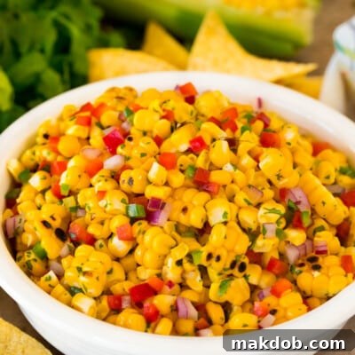 A bowl of fresh corn salsa surrounded by crispy tortilla chips.