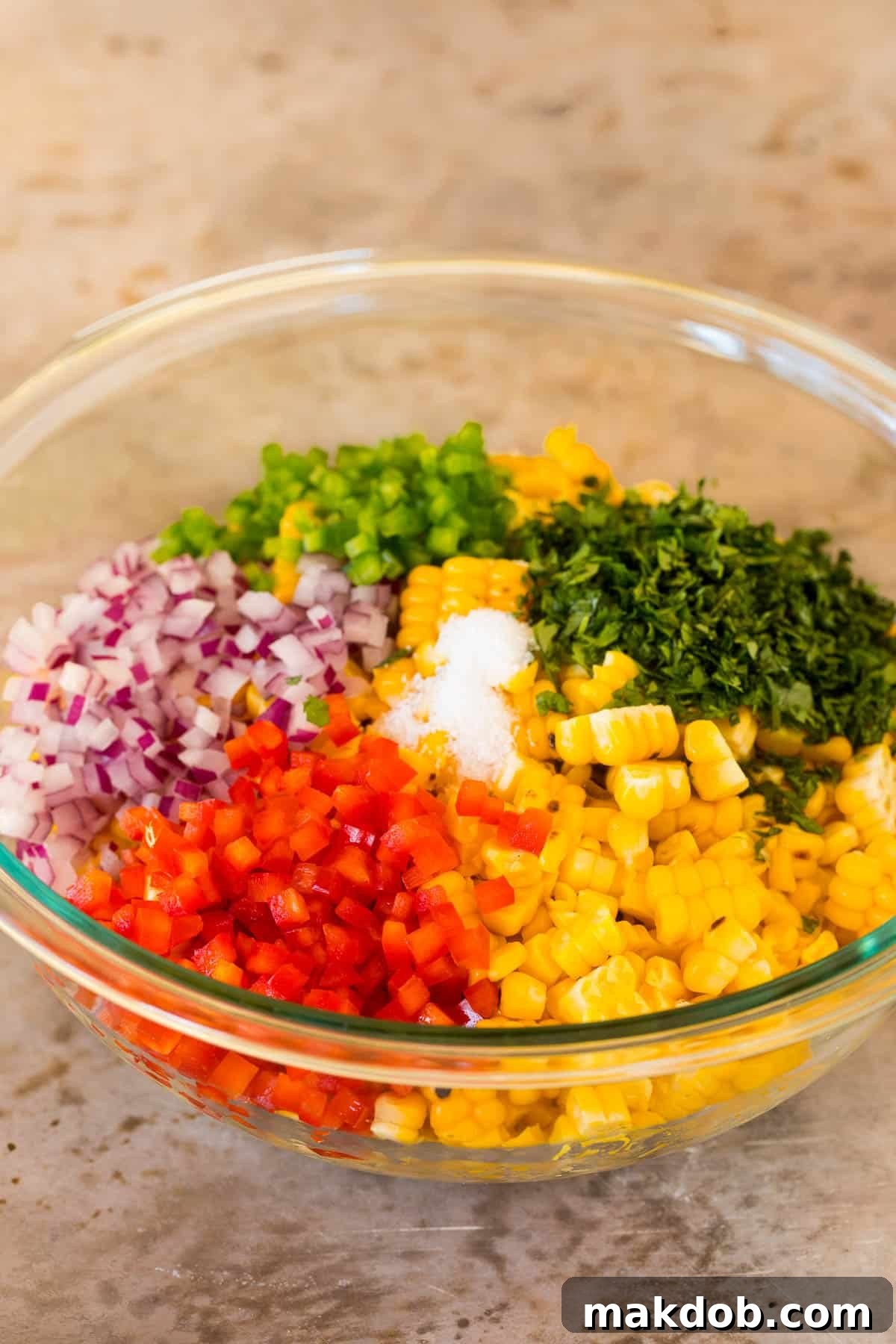 A close-up of a bowl filled with vibrant corn salsa, showcasing the fresh kernels, peppers, onions, and cilantro, lightly seasoned with salt.