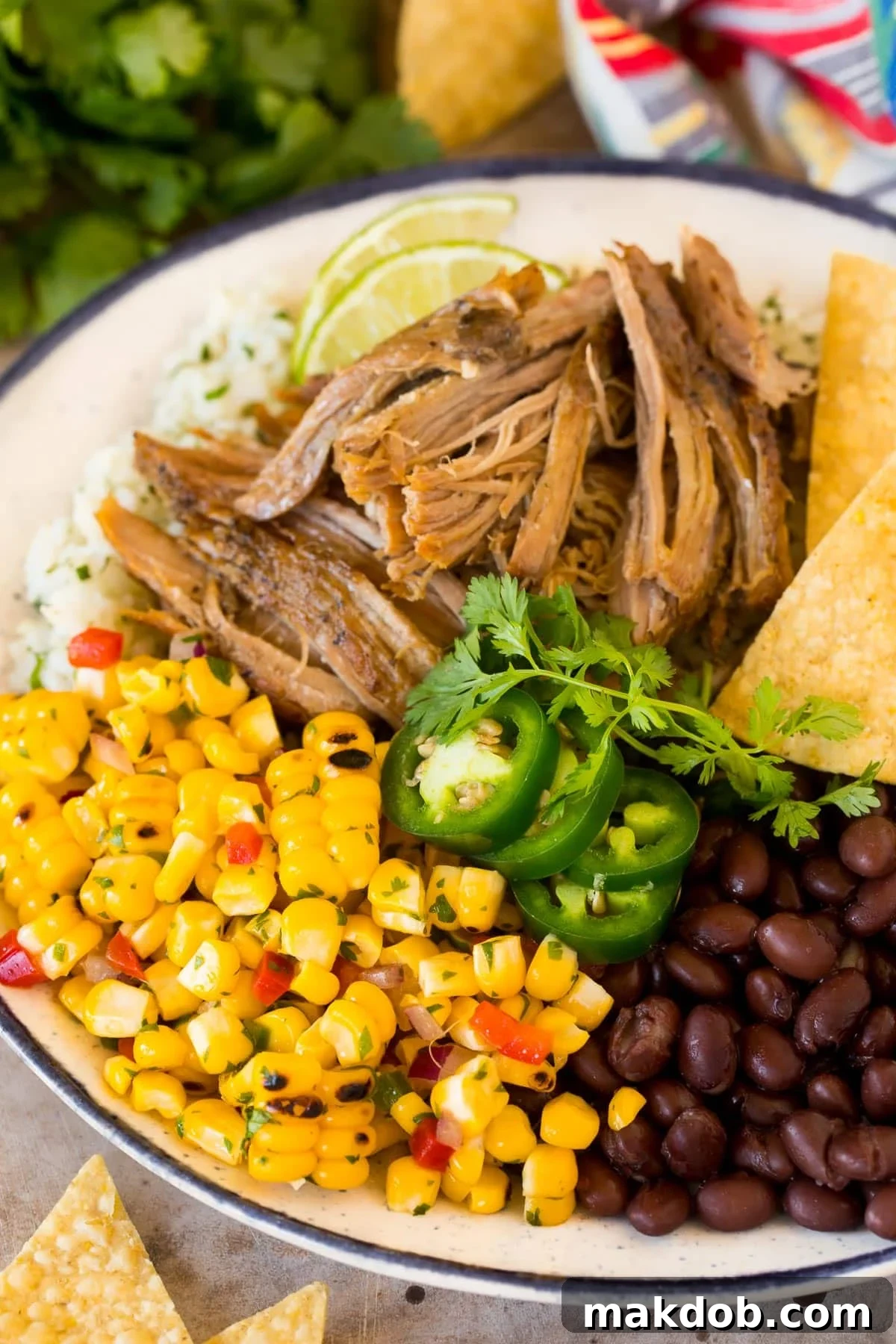 A plate of grilled pork served with a generous dollop of fresh corn salsa, alongside rice and black beans.