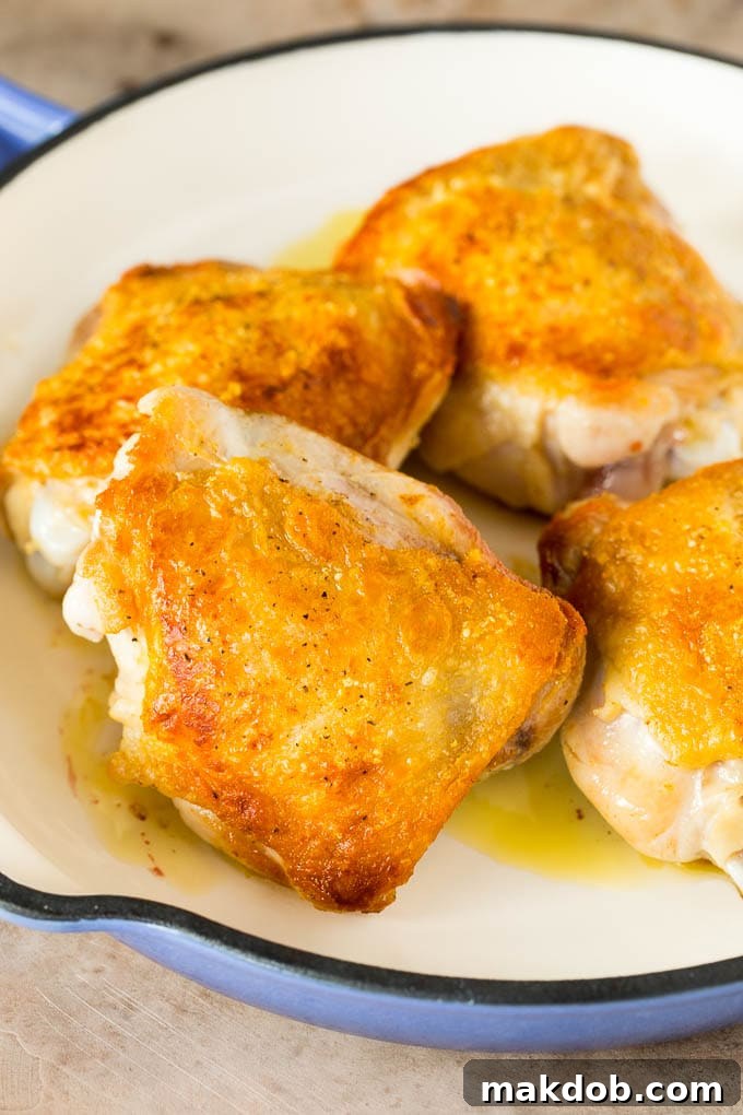 Browned chicken thighs simmering in a pan with the sauce.