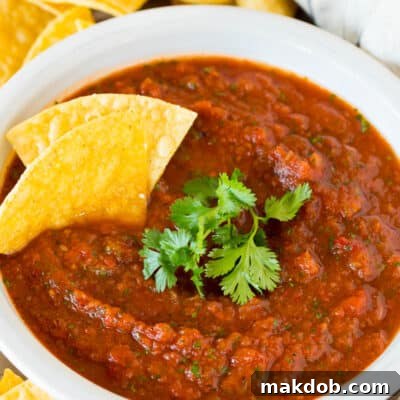 A bowl of chipotle salsa topped with fresh cilantro and tortilla chips.