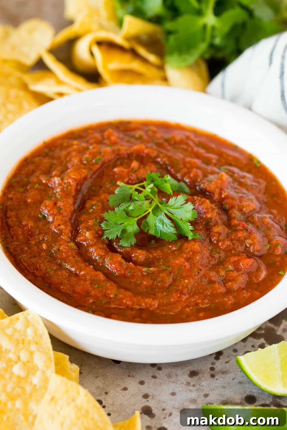 A beautifully presented bowl of homemade chipotle salsa, generously garnished with fresh cilantro leaves, highlighting its vibrant color and freshness.