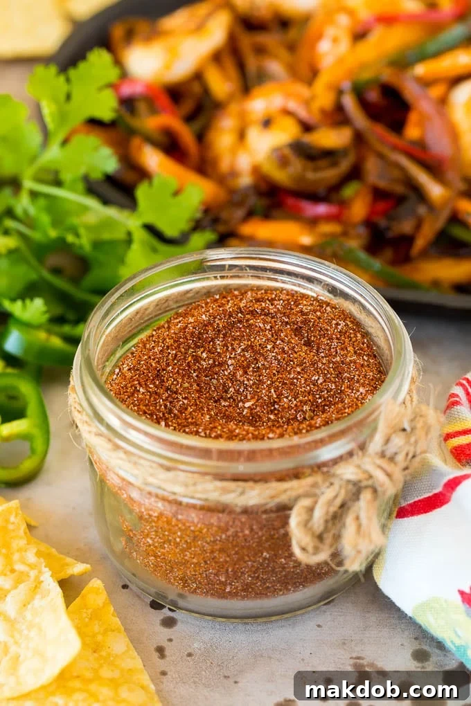 A close-up of a glass jar filled with vibrant homemade fajita seasoning, showcasing the rich colors of chili powder, paprika, and cumin.