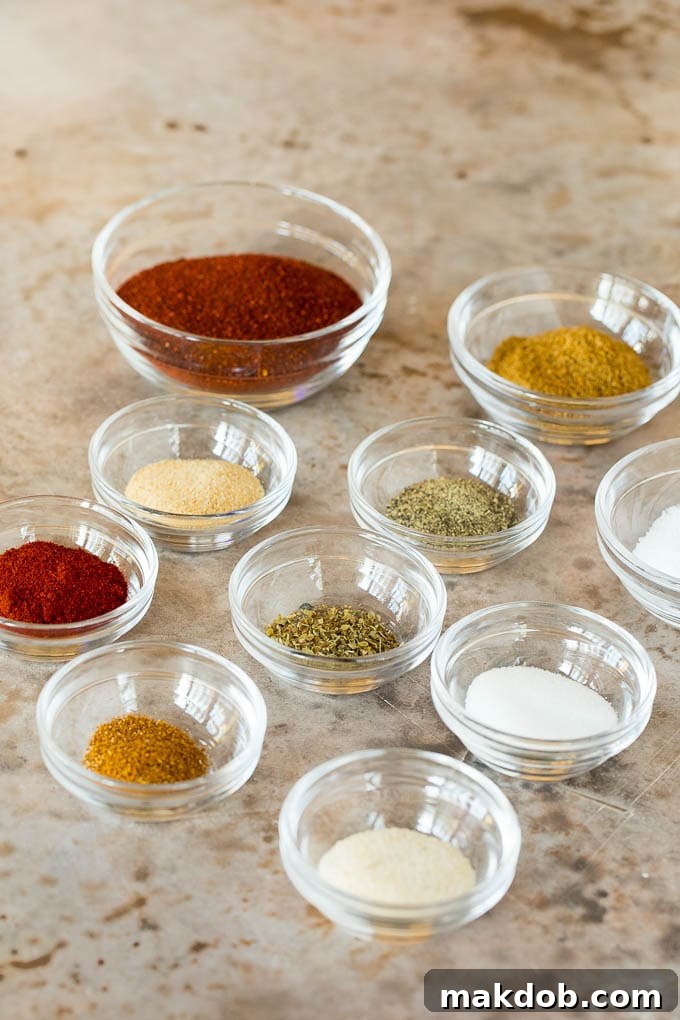 An array of small bowls filled with individual fajita seasoning ingredients like chili powder, cumin, and paprika, ready to be mixed.