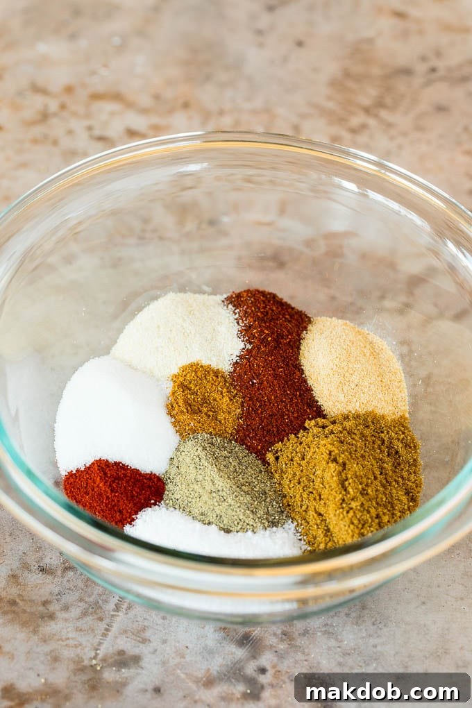 Hands stirring a bowl of various ground spices and herbs, mixing them into a cohesive fajita seasoning blend.