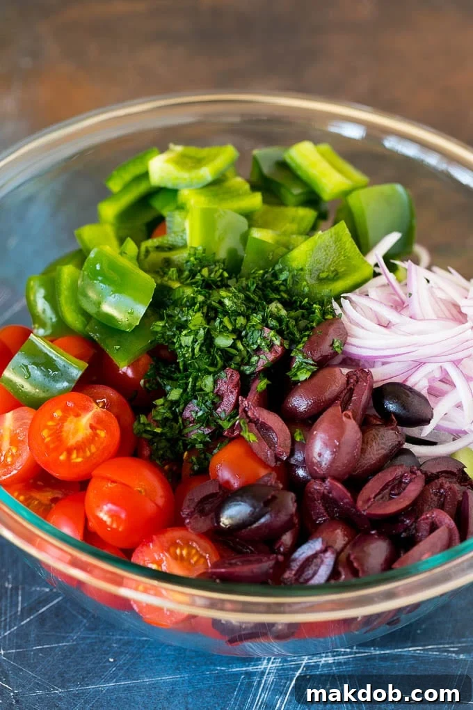 Mediterranean Sunshine Salad 4 A selection of cherry tomatoes, cucumbers, bell peppers, and olives in a bowl, showcasing fresh ingredients.